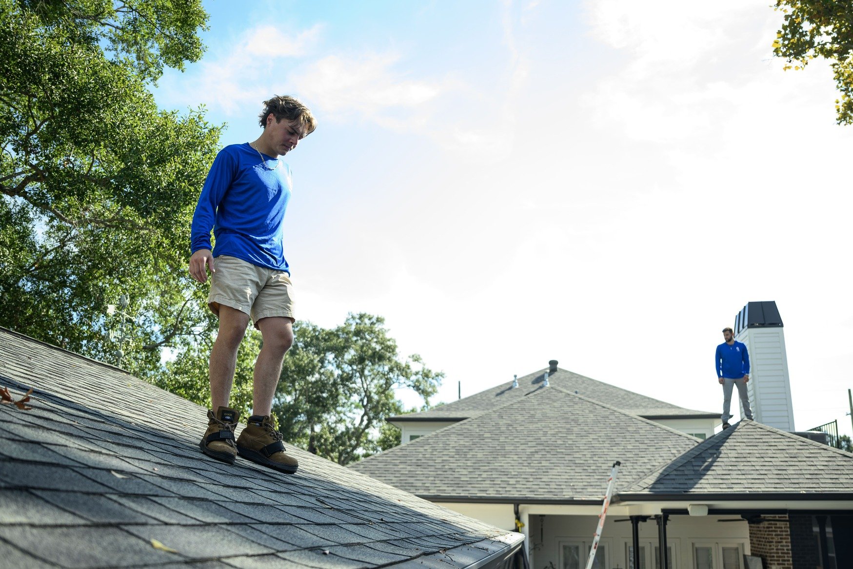 Epic Roofing crew member standing on a shingle roof with neighbouring rooftops behind