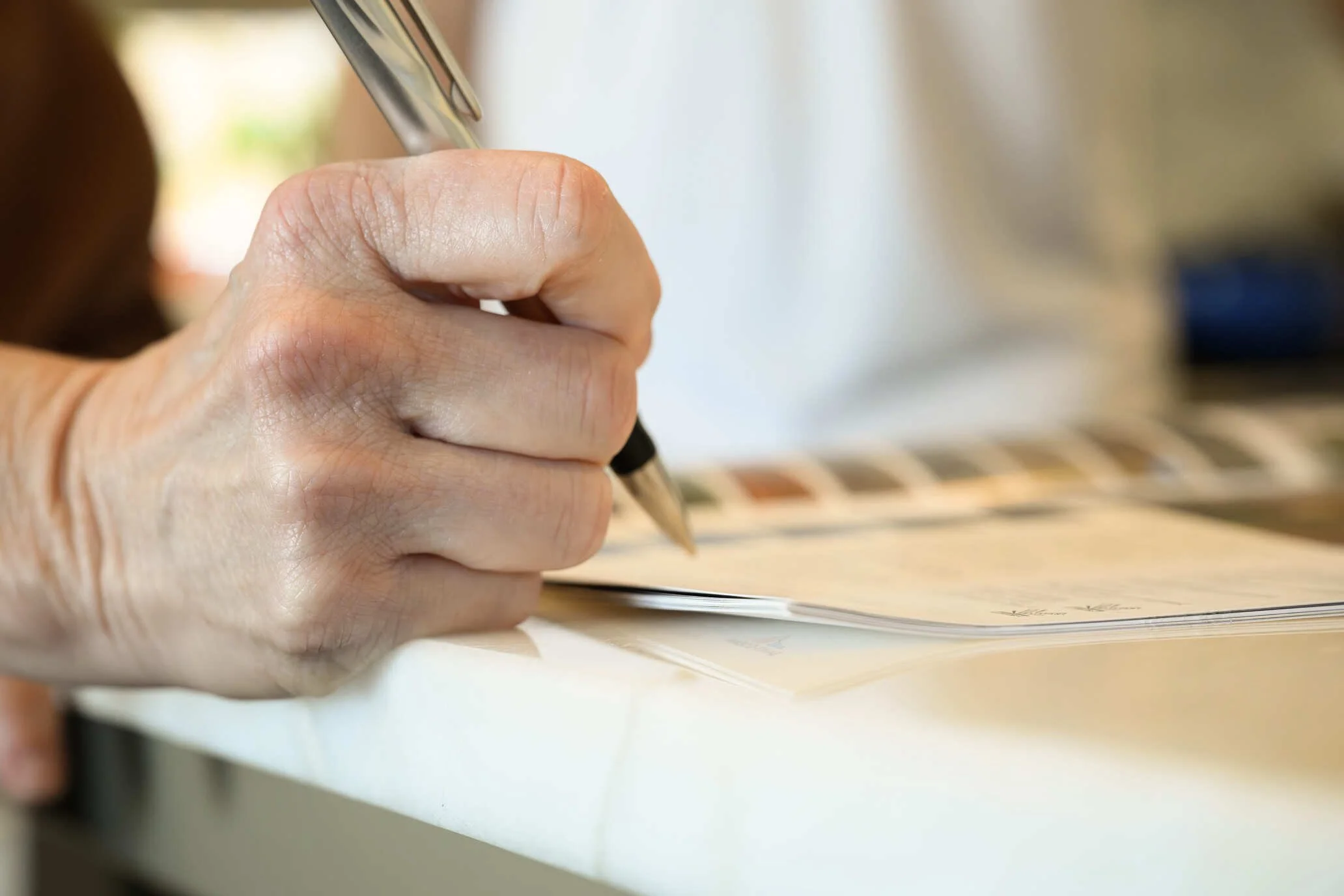 Close-up of a hand signing paperwork on a table