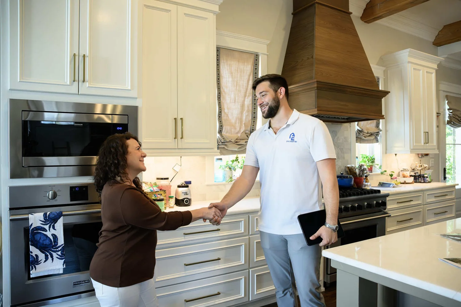 Epic Roofing estimator shaking hands with a homeowner in a kitchen