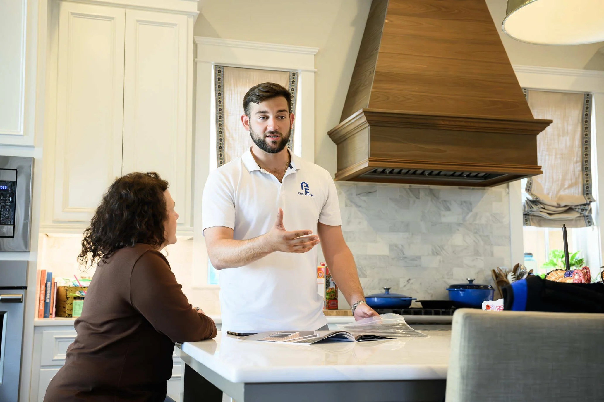 Epic Roofing estimator talking with a homeowner in a kitchen