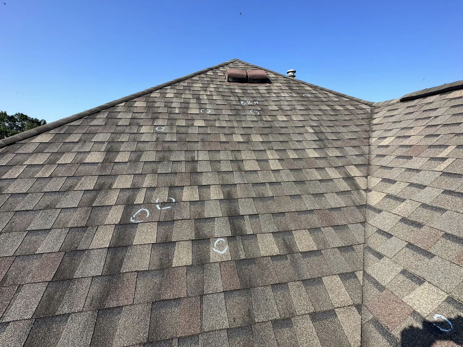 Grey shingle roof slopes meeting at a ridge under a blue sky