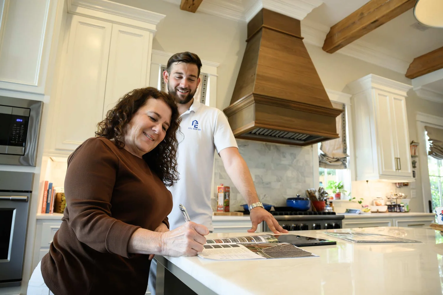 Epic Roofing estimator and homeowners talking at a kitchen island