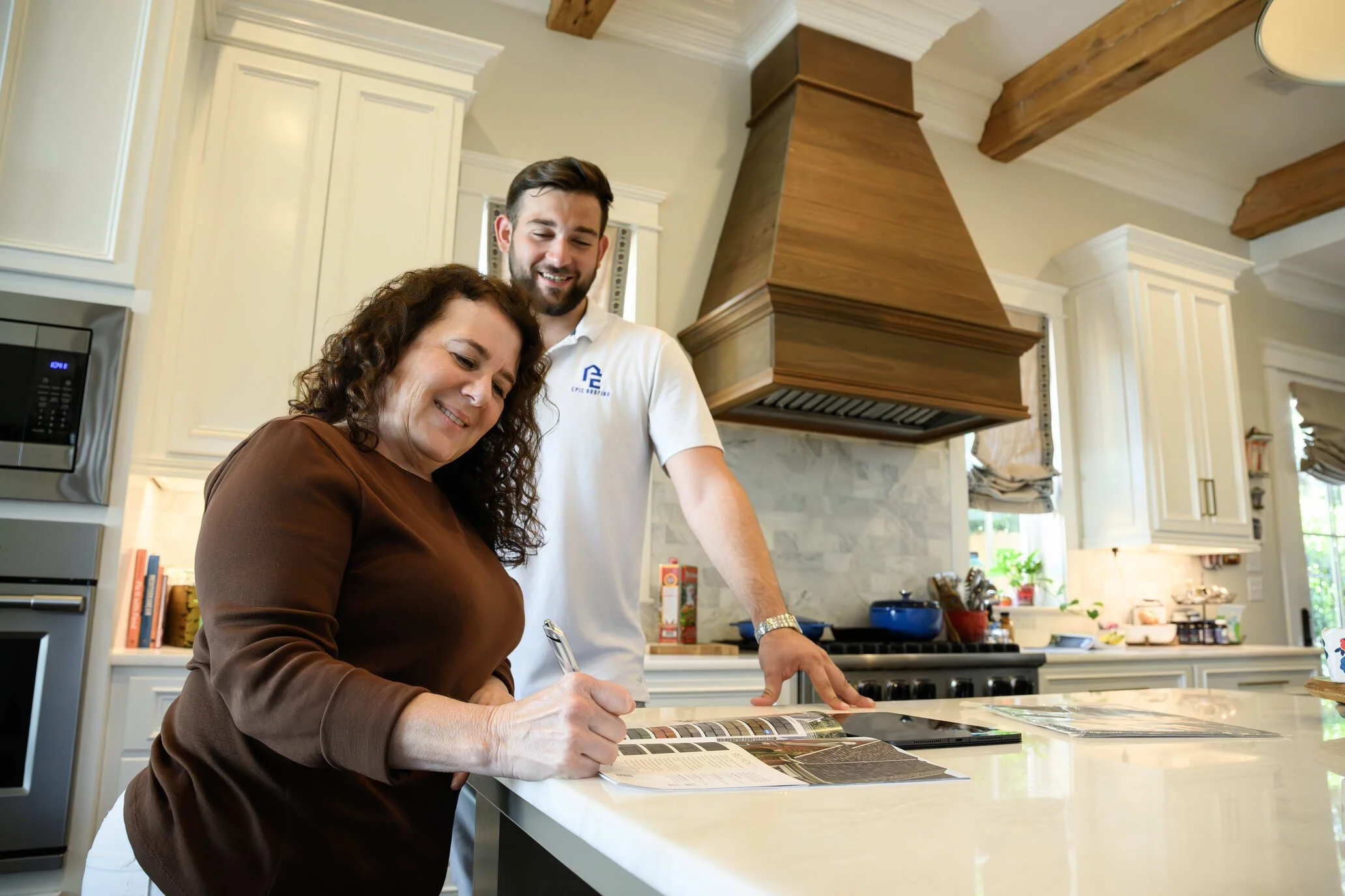 Epic Roofing estimator and homeowners talking at a kitchen island