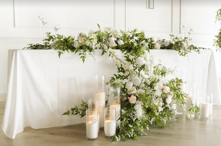 Silk greenery garland running along a head table with candles