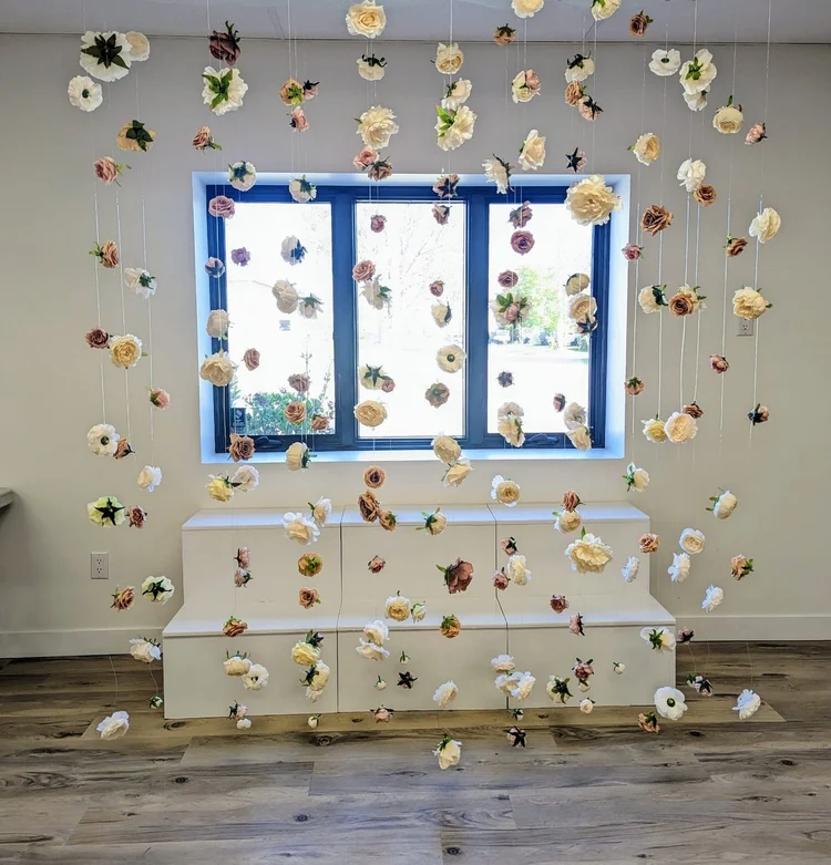 Floating floral wall of suspended blooms in front of a window