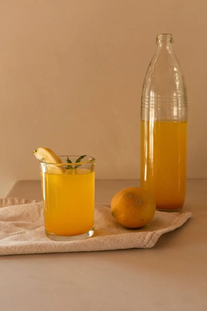 A citrus cooler beside a bottle of infusion