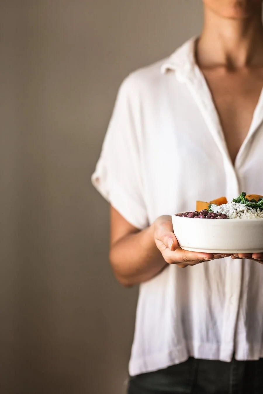 Claire holding a bowl of grains, beans, roasted squash and greens