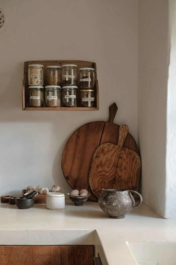 A kitchen corner with a shelf of spice jars and wooden boards