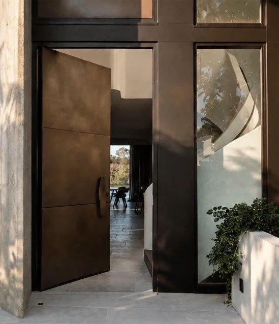 Modern architectural entrance with bronze door and natural light