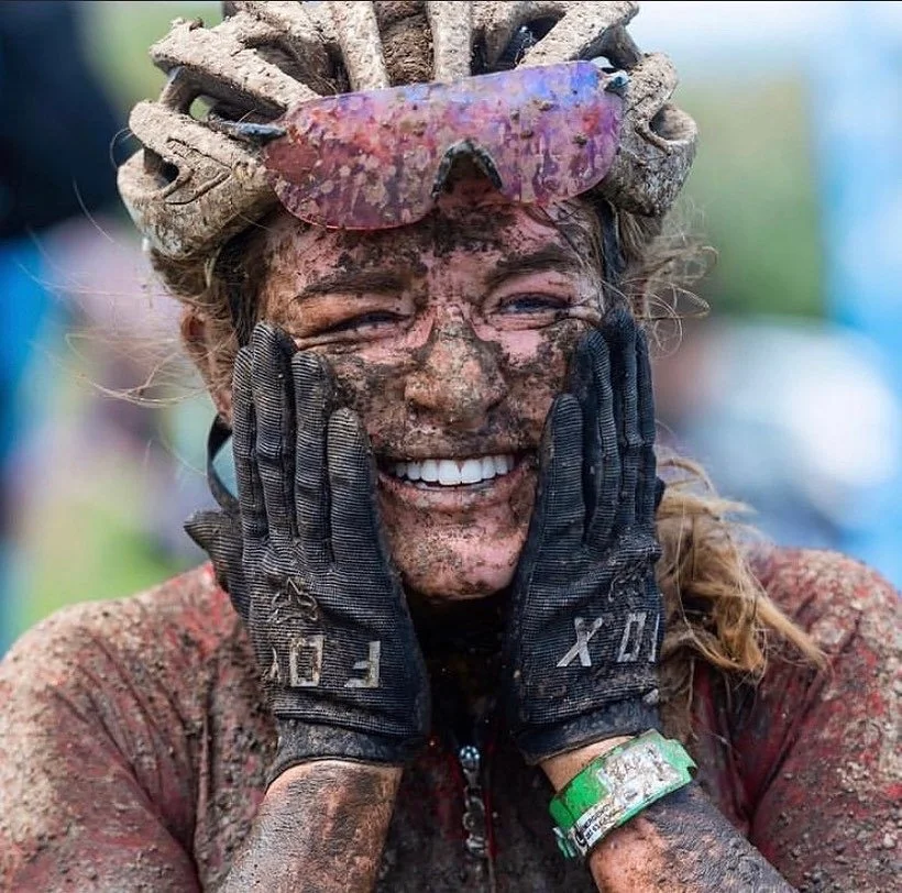 Amy Wakefield covered in mud and smiling after a mountain bike race