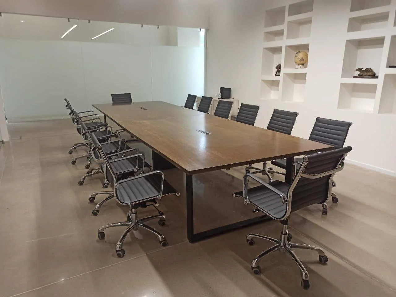 Sala de juntas con mesa de madera y sillas ejecutivas
