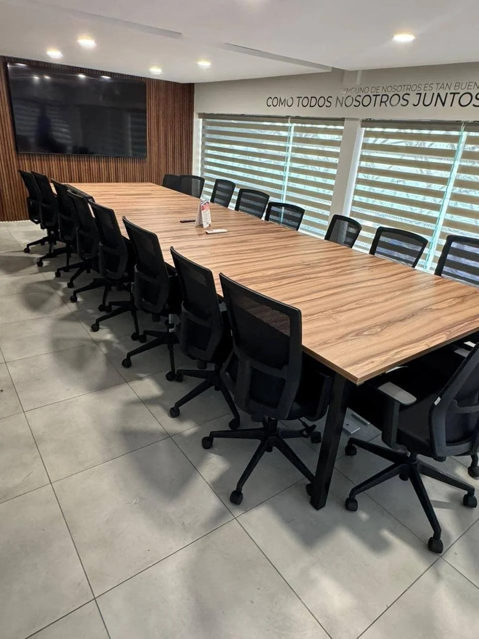 Sala de consejo con mesa de madera y 16 sillas negras
