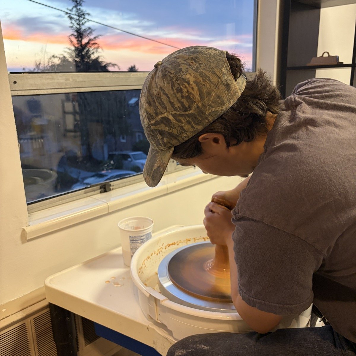 Clay Club member working at a pottery wheel at sunset