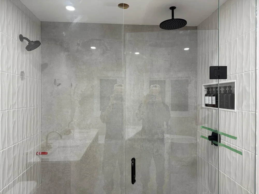 Finished marble shower with rainfall head and hand shower, plumbed by Seal Plumbing