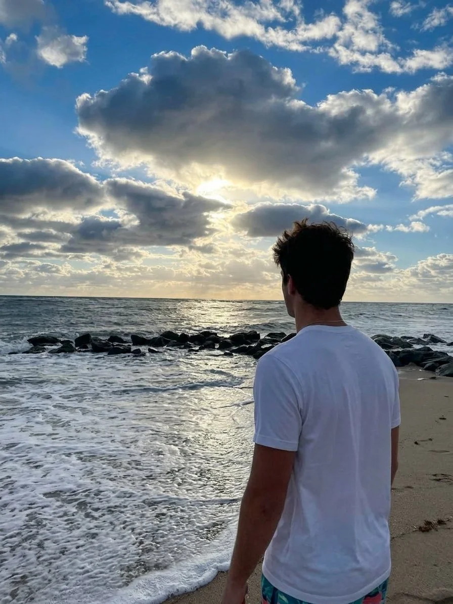 Gregory Gabler on the beach at sunrise, looking out over the ocean