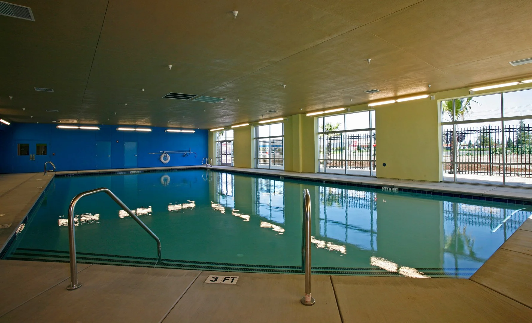 The indoor pool, still water the length of a daylit room with tall windows along the right.