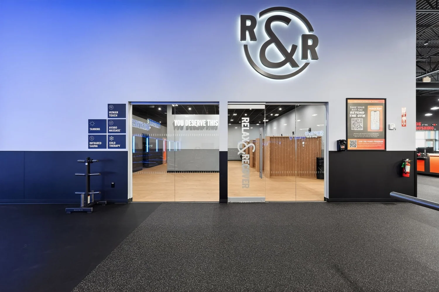 The entrance to the recovery suite, an R and R monogram on a blue wall above glass doors.