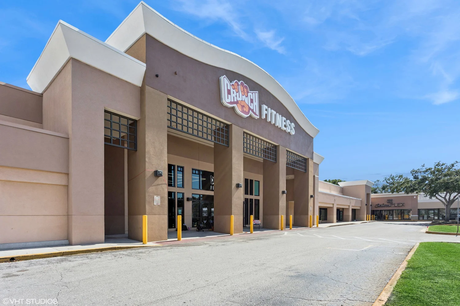 A Crunch club in beige stucco with tall white gables over the entrance and glass doors beneath the sign.