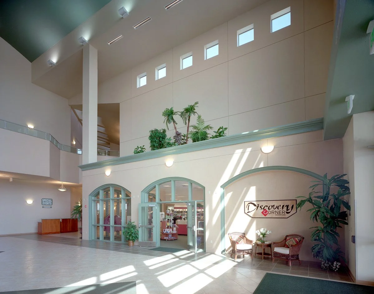 A corner of the lobby, two arched doorways into the bookstore with sun falling in stripes across the tiled floor.