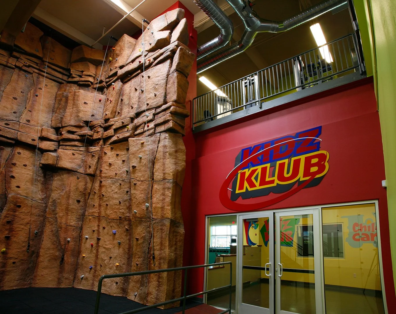 The climbing wall, a moulded rock face the full height of the building above the Kidz Klub doors.