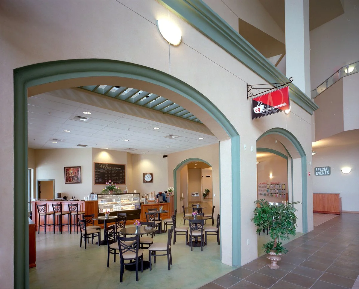 The Common Grounds coffee shop through a wide green trimmed arch off the lobby, tables filling the floor.