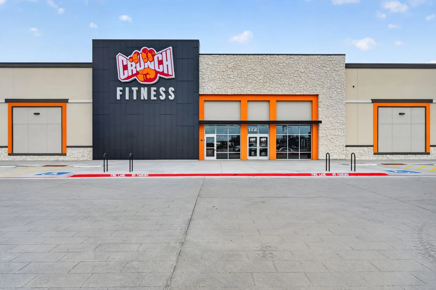 A navy sign block carrying the Crunch Fitness logo set into a stone and stucco front.