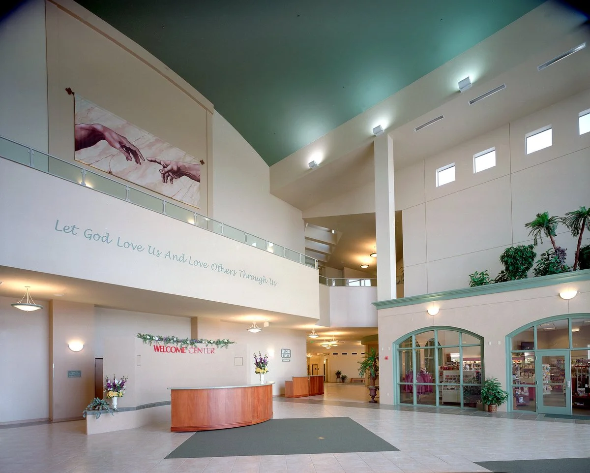 The lobby, a curved wooden desk under a red Welcome Center sign, lettering along the balcony above.