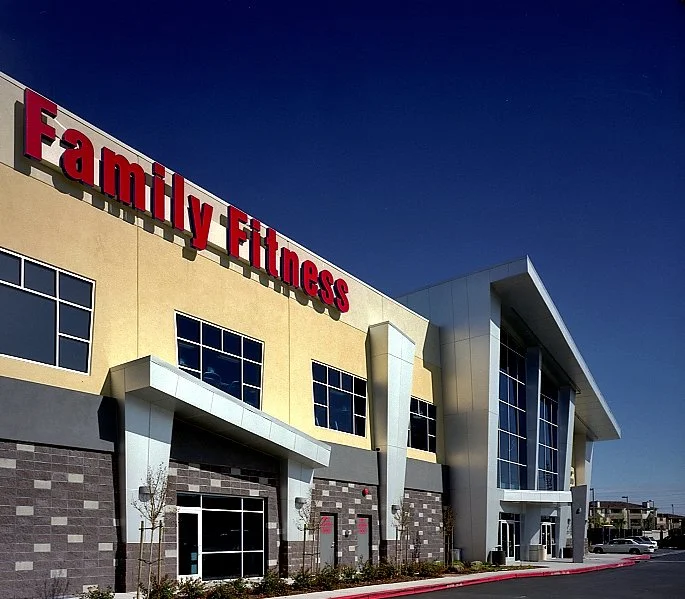 Red Family Fitness lettering mounted large on the tan upper wall above the grey stone base.