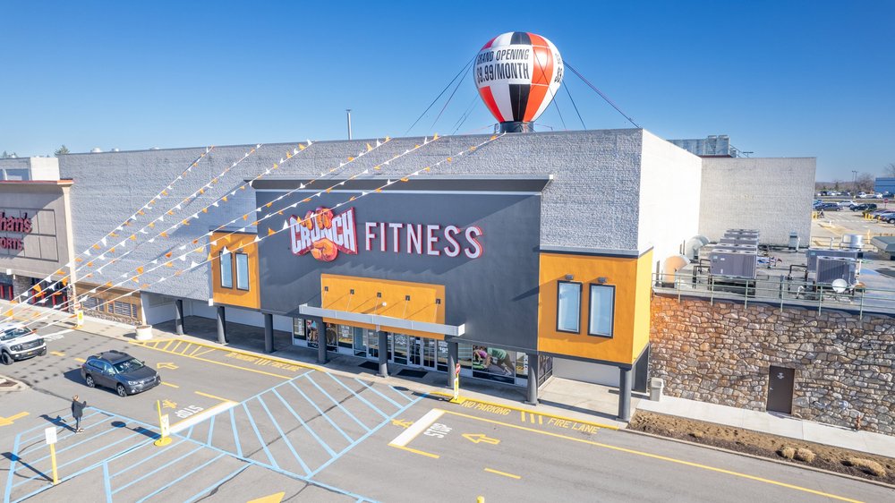 A grey masonry front with a dark sign block and orange panels, strings of bunting running across it.