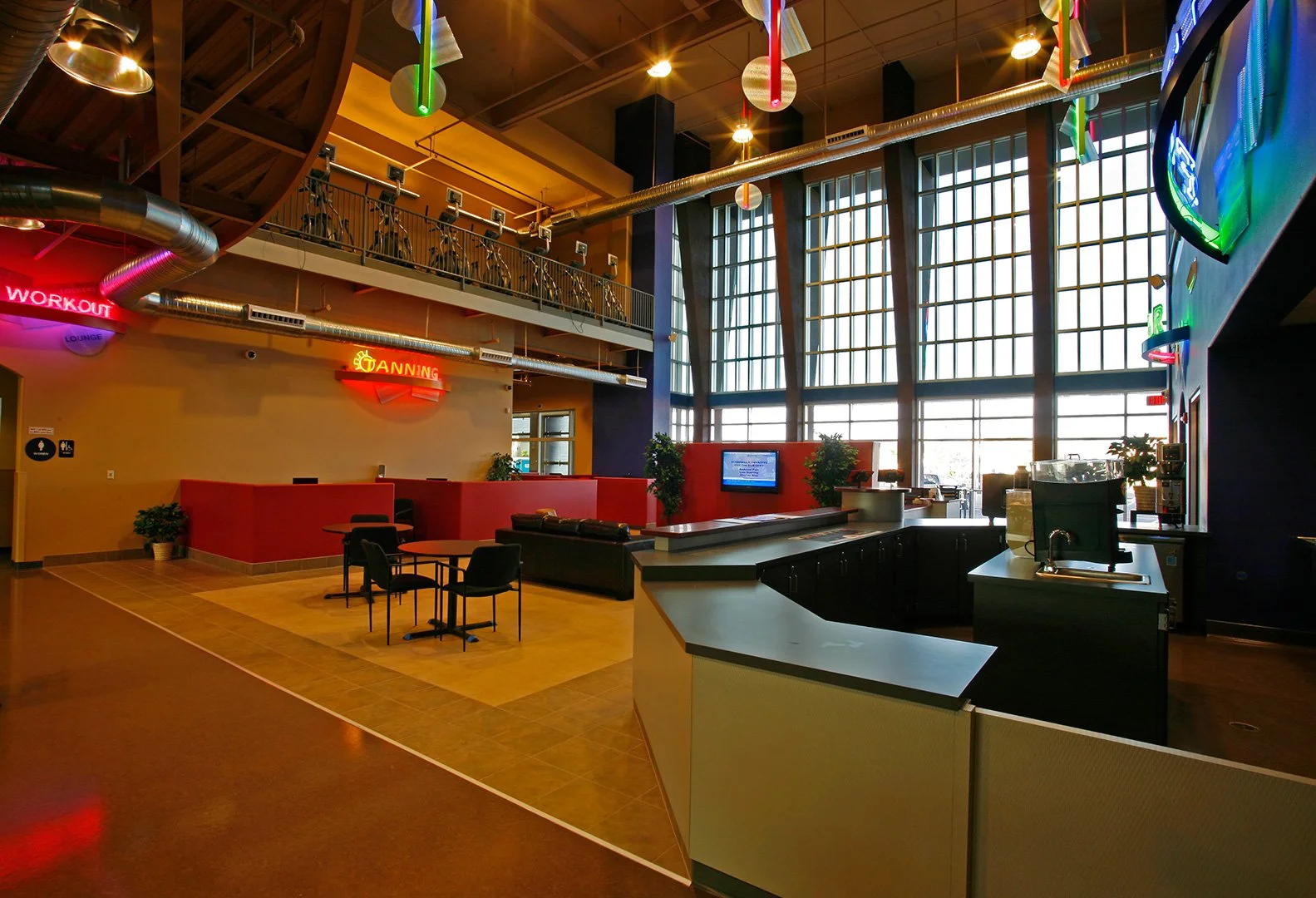 The double height entrance hall, a curved reception and juice counter with WORKOUT and SPINNING in neon behind.