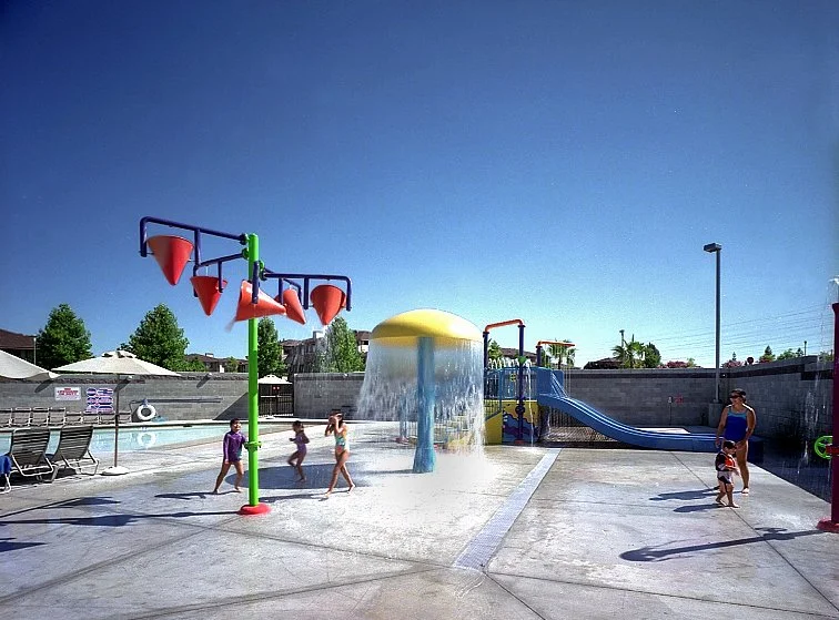 The childrens spray ground, a yellow mushroom fountain and a tipping bucket frame over a painted concrete deck.
