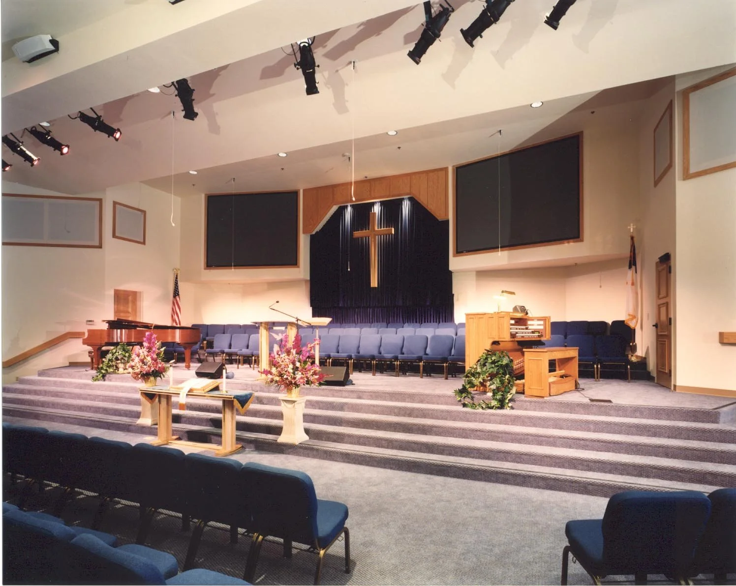 The platform from the floor, a wooden cross between two screens with choir seating, piano and organ ranged behind.