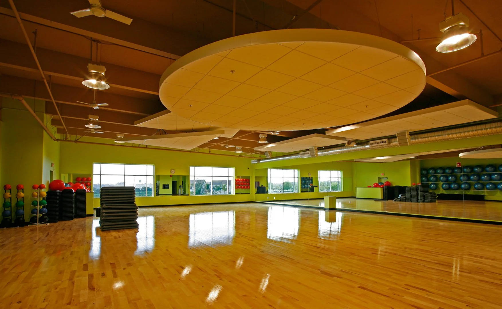 The same studio the long way, the disc edge on under the open timber deck, racked balls and mats down both sides.