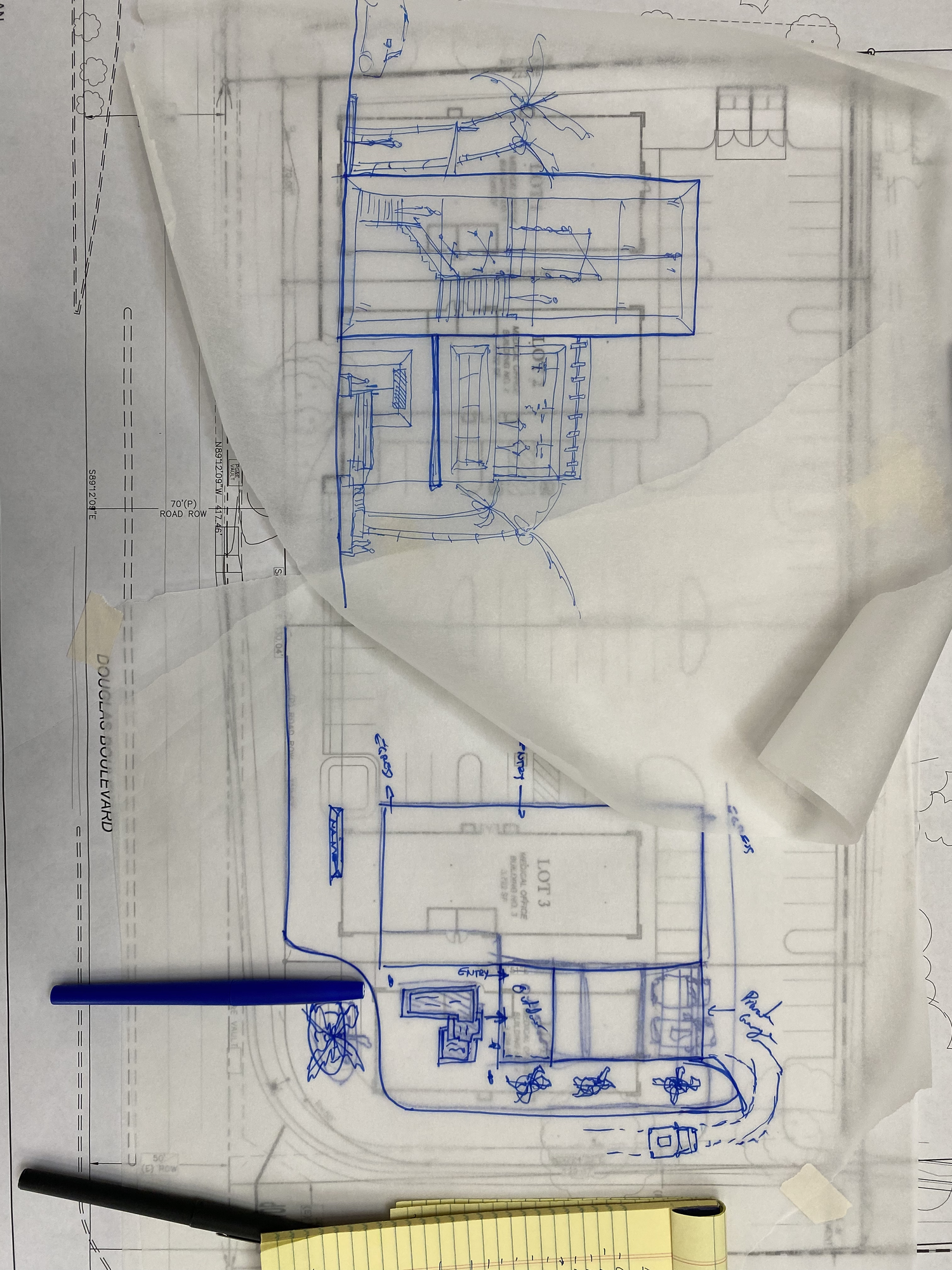 The first sketch, in blue pen on tracing paper laid over the site plan, laying out an early scheme for the building.