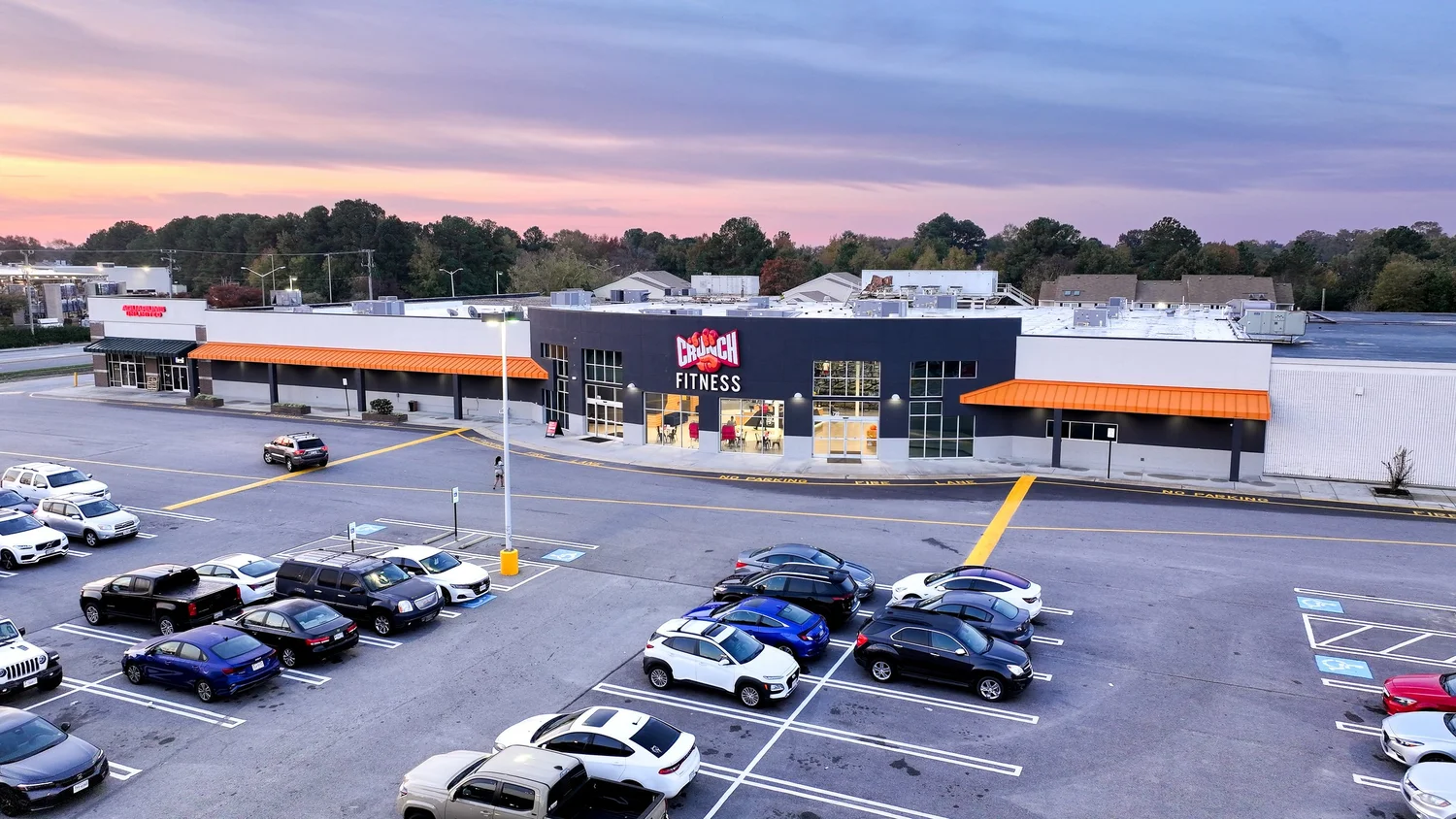 A dark box with orange awnings each side of its glazed entrance, the sky pink behind it at dusk.
