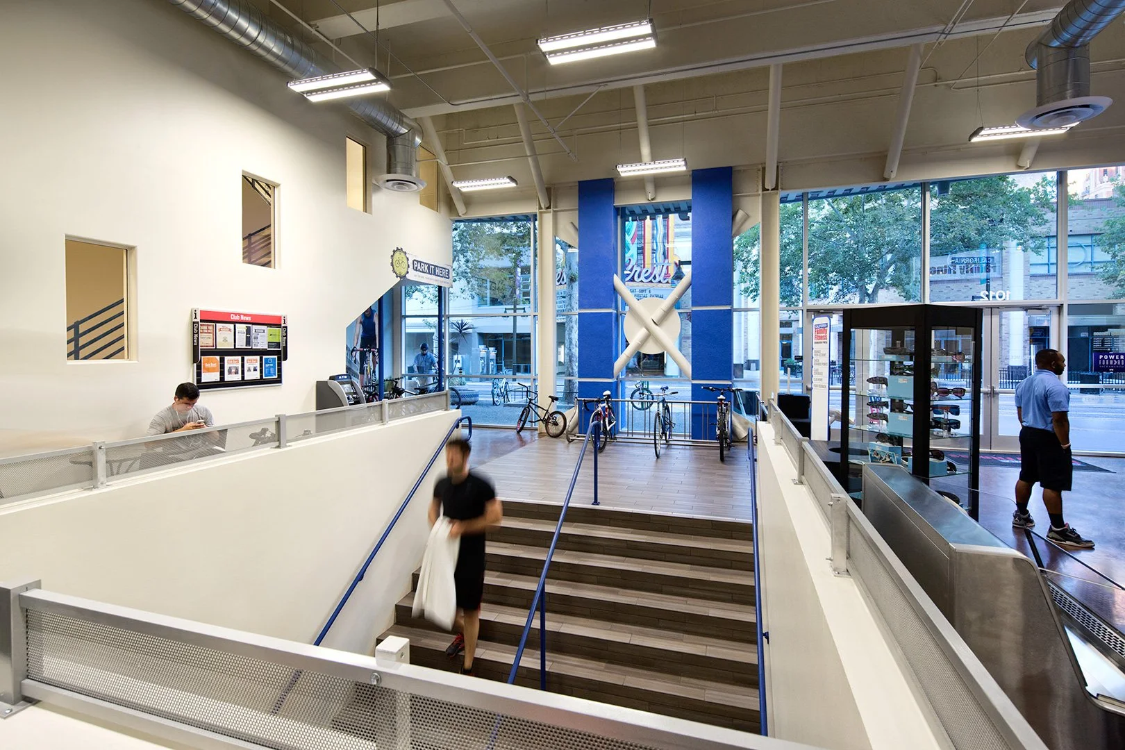 Down the open stair just inside the door, timber treads dropping between blue and steel handrails to the club.