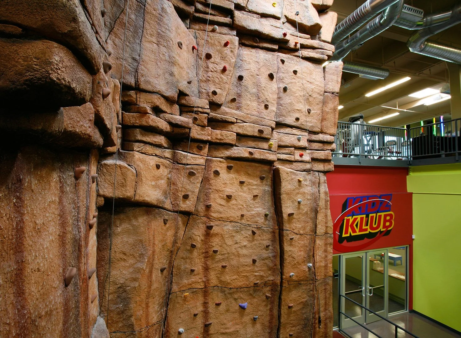 The climbing wall close to, the moulded rock face and its bands of holds filling most of the frame.