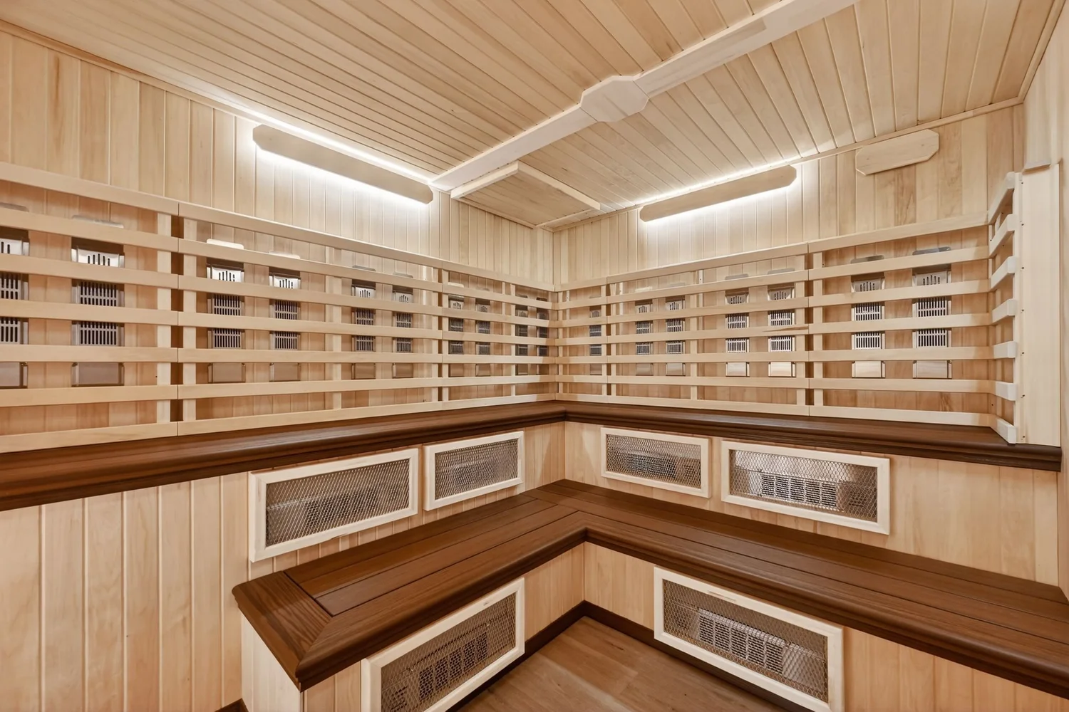 An infrared sauna lined in pale timber, slatted heater panels above a bench on three sides.