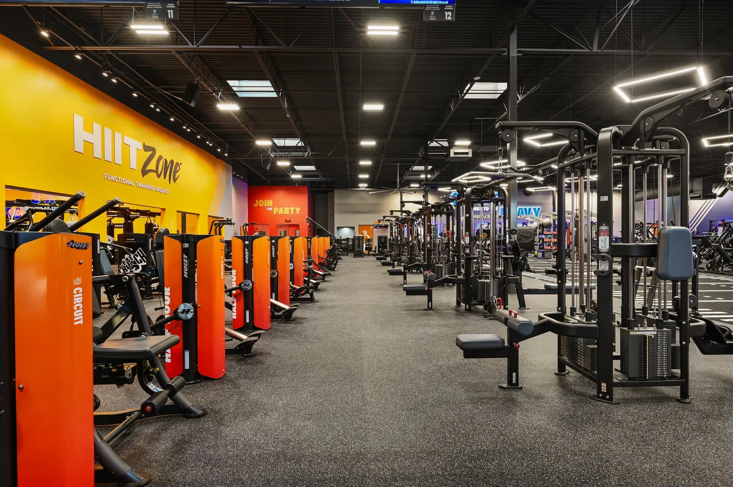 The HIIT Zone, a run of orange circuit machines along a yellow wall under the HIIT Zone sign.