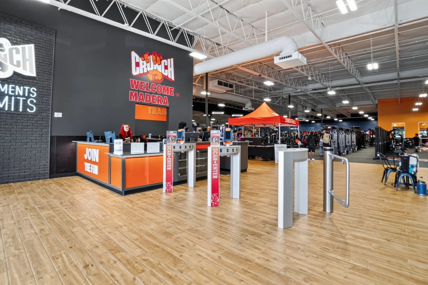 The welcome desk inside the entrance, an orange and black counter facing a row of turnstiles.