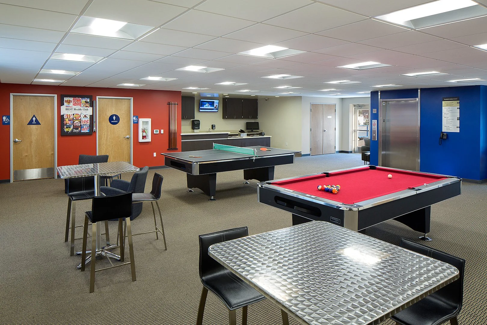The games room, a red felt pool table and table tennis table between a red wall and a deep blue one.