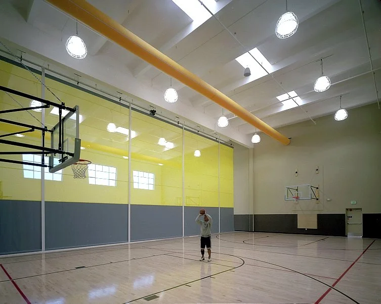 The indoor court, one player at the centre line with the racquetball glazing to the left.