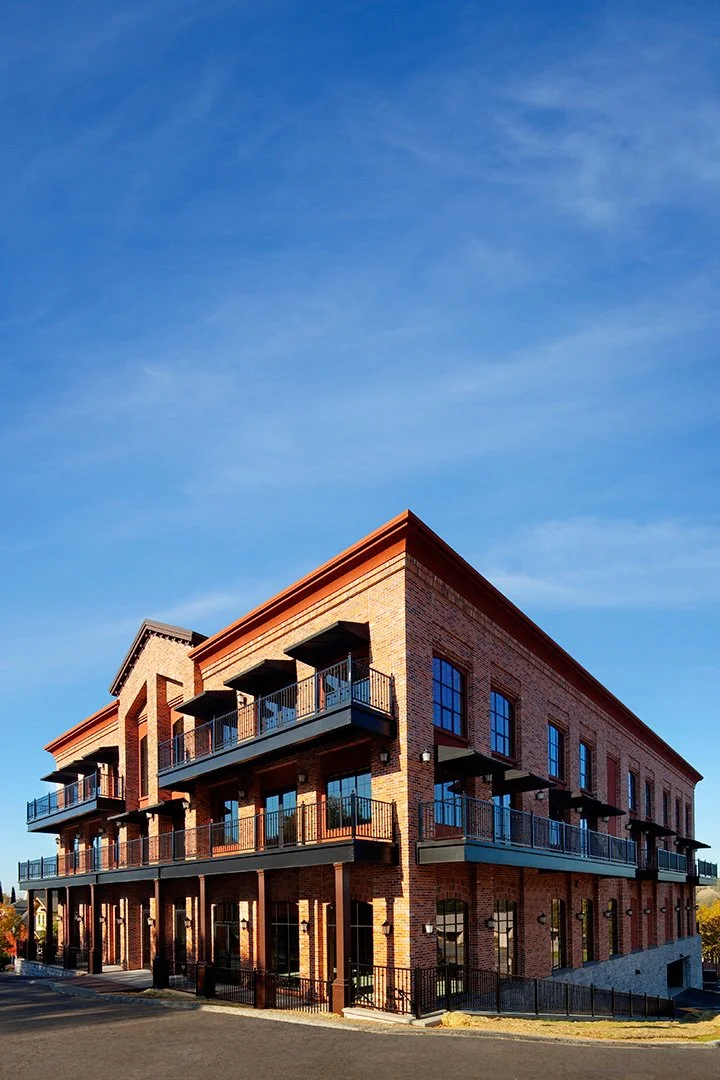 The whole building from its corner under a deep blue sky, balconies stepping along both elevations.