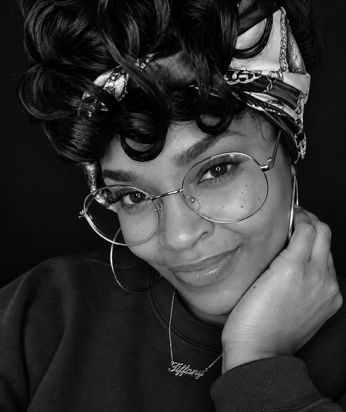 Tiffany Bella smiling in glasses and a patterned headscarf