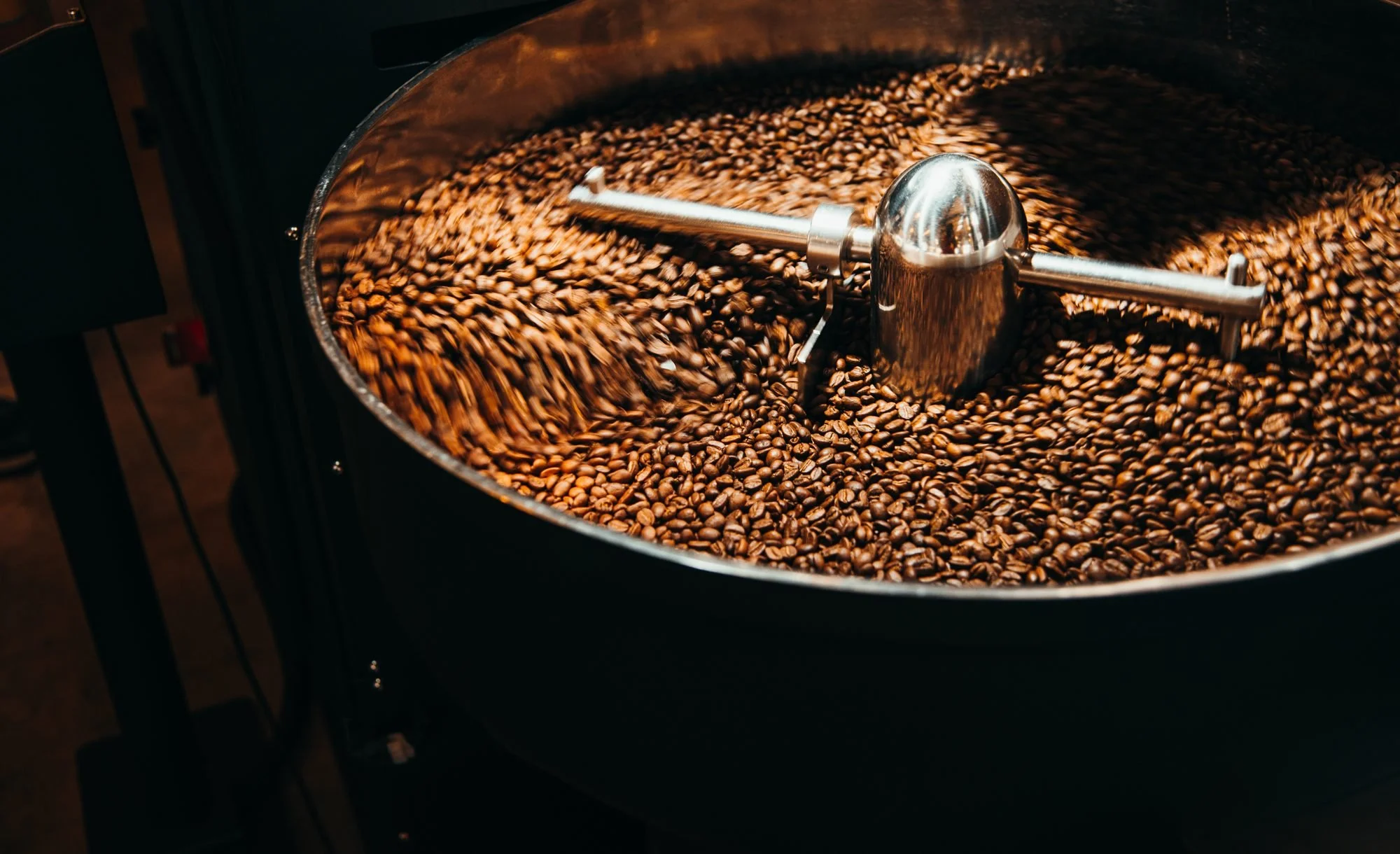Roasted coffee turning under the stirring arm of a cooling tray