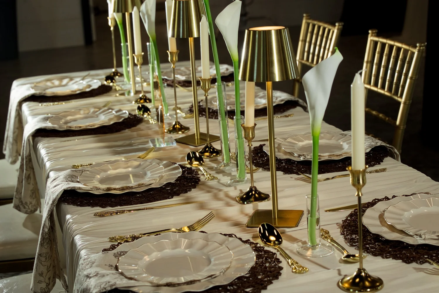 A candlelit tablescape with gold lamps, calla lilies and ivory linens