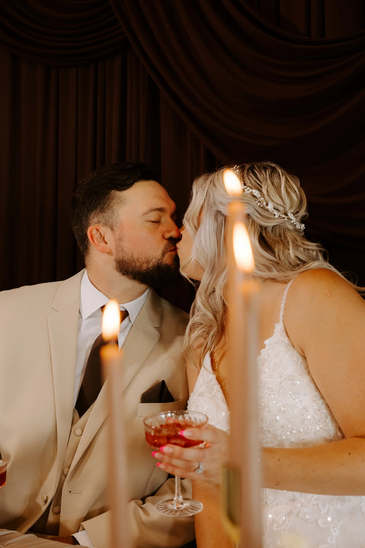A bride and groom sharing a candlelit kiss