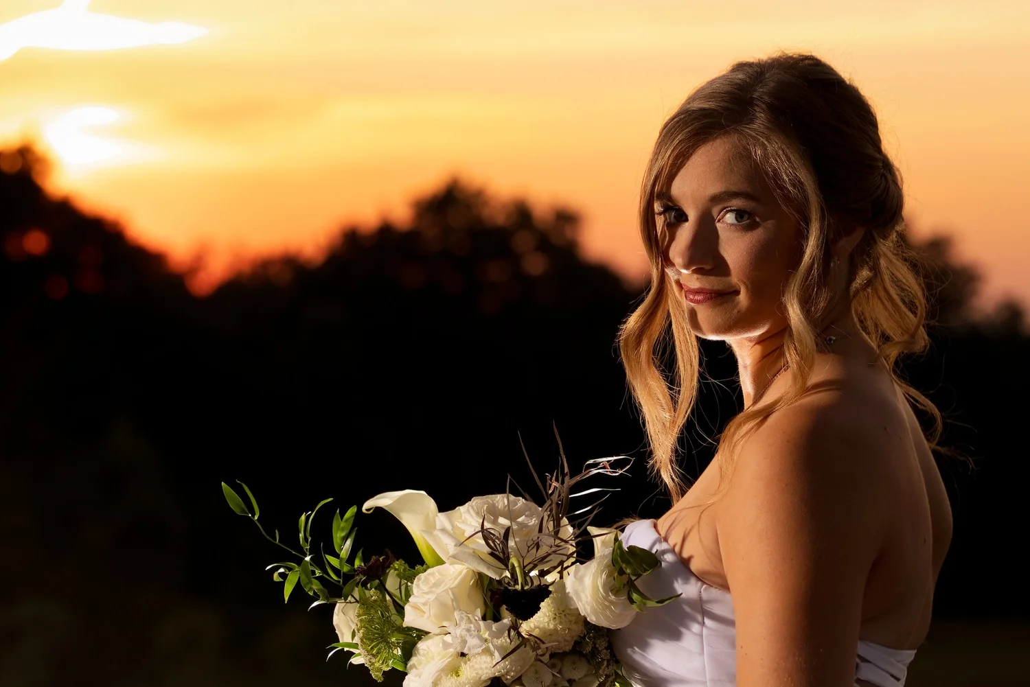 A bride holding her bouquet at sunset