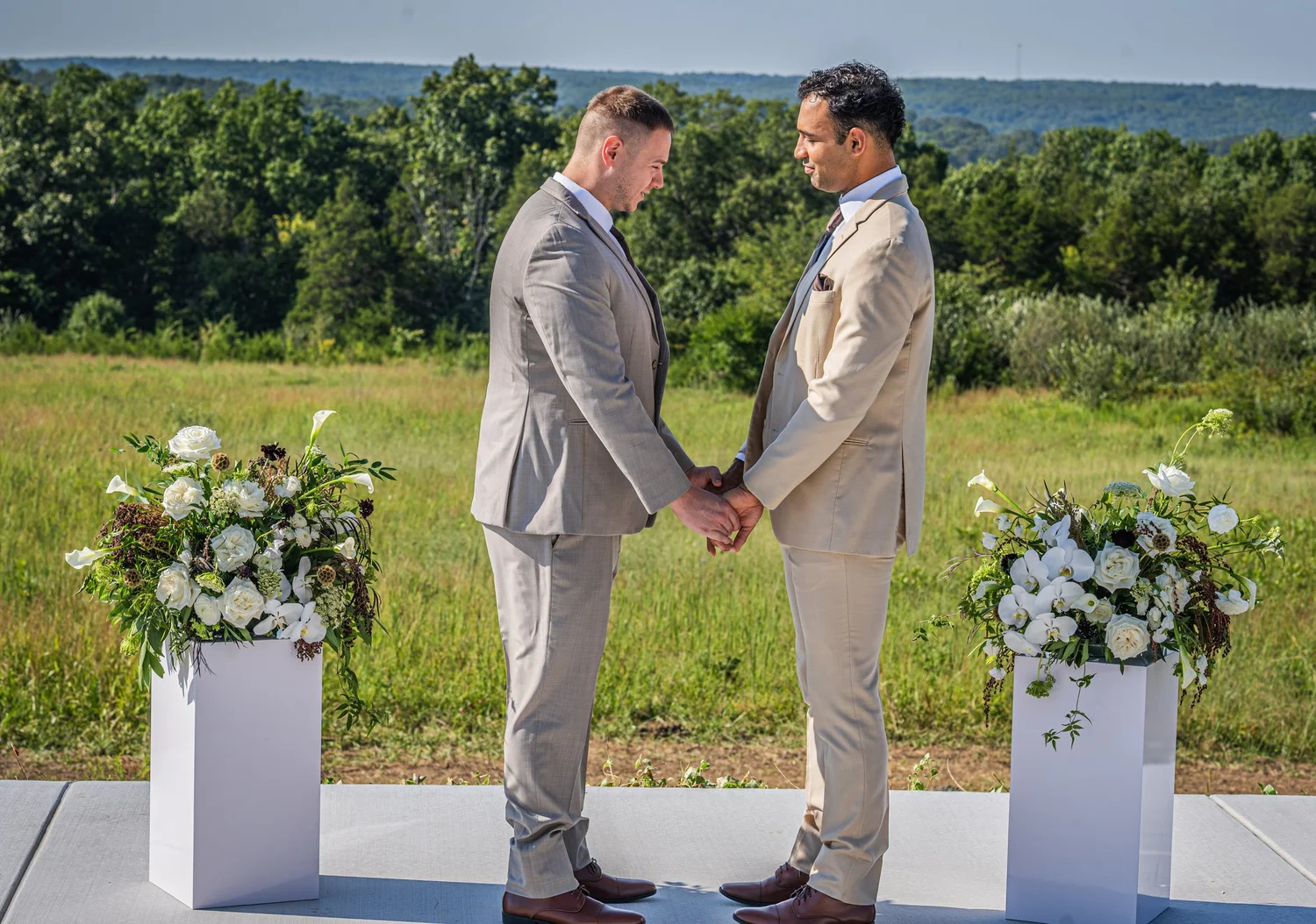 Two grooms holding hands at their outdoor ceremony