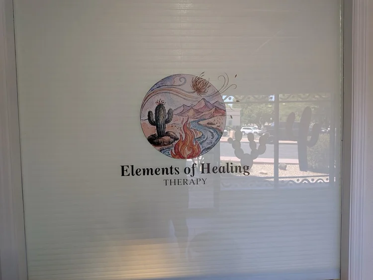 The Elements of Healing Therapy watercolor logo on the office window — cactus, desert mountains, river, and flame